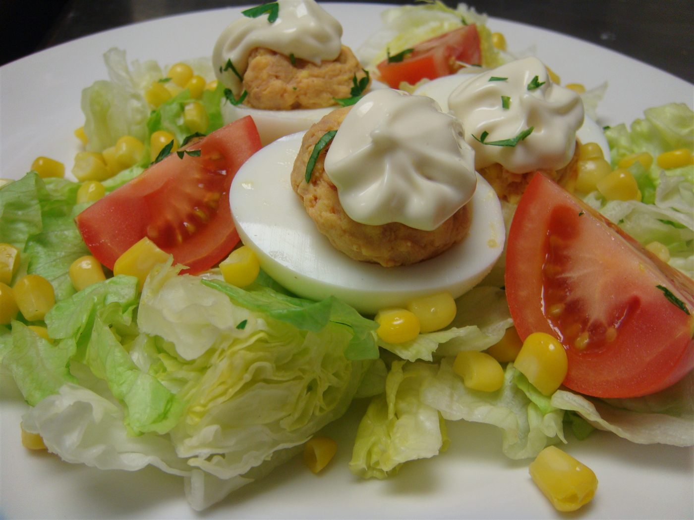 Ensalada de huevos rellenos con lechuga, tomate y maíz